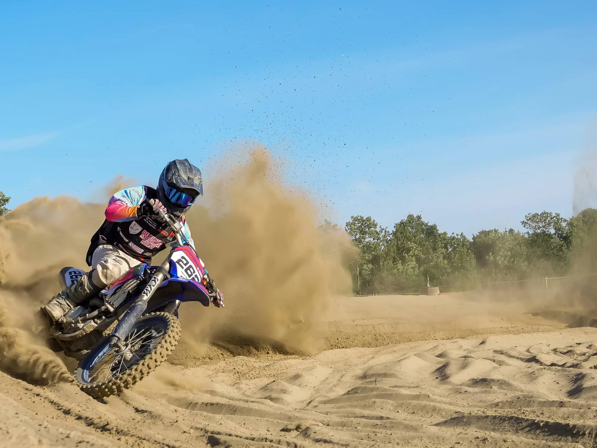 Project Jeugd MX ZVL van Zeeuwsweb: jonge motorcrosser in een bocht op een zandcircuit, met opstuivend zand achter de motor
